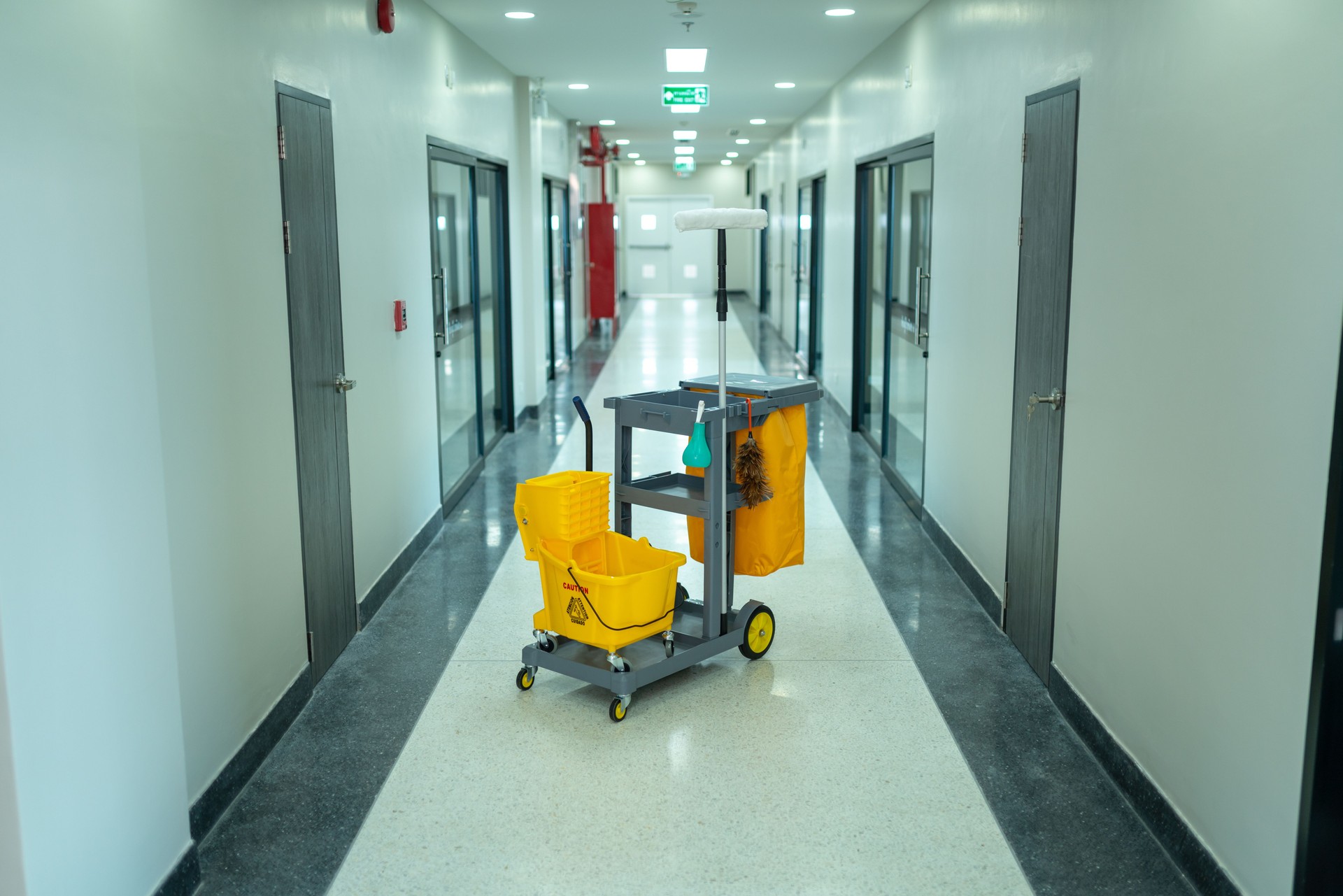 A yellow cleaning cart is in the middle of a hallway